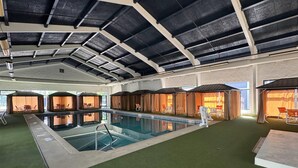 Une piscine intérieure dotée d’un plafond haut et d’un éclairage artificiel.