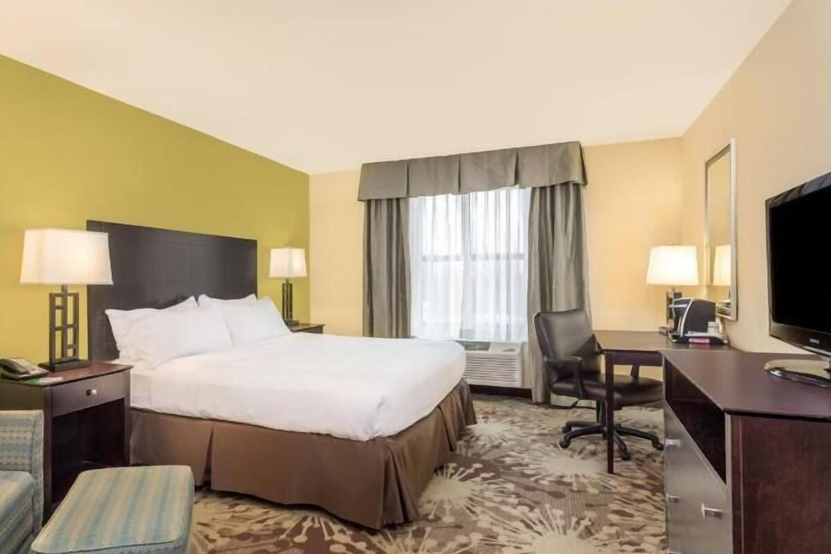A hotel room with a bed, a desk, a chair, a telephone, and a television.