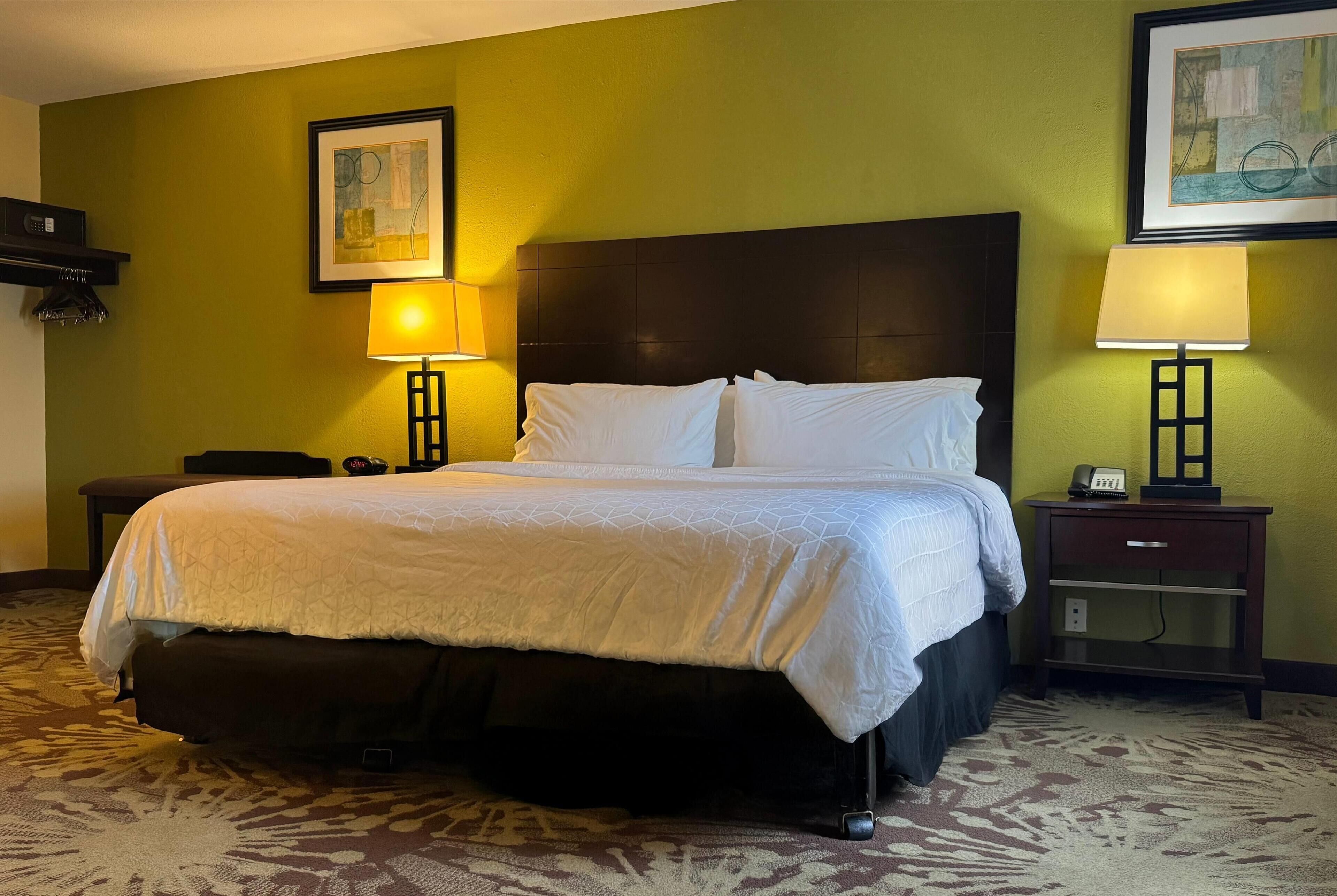 A hotel room with a large bed, two bedside tables, and two wall-mounted lamps.