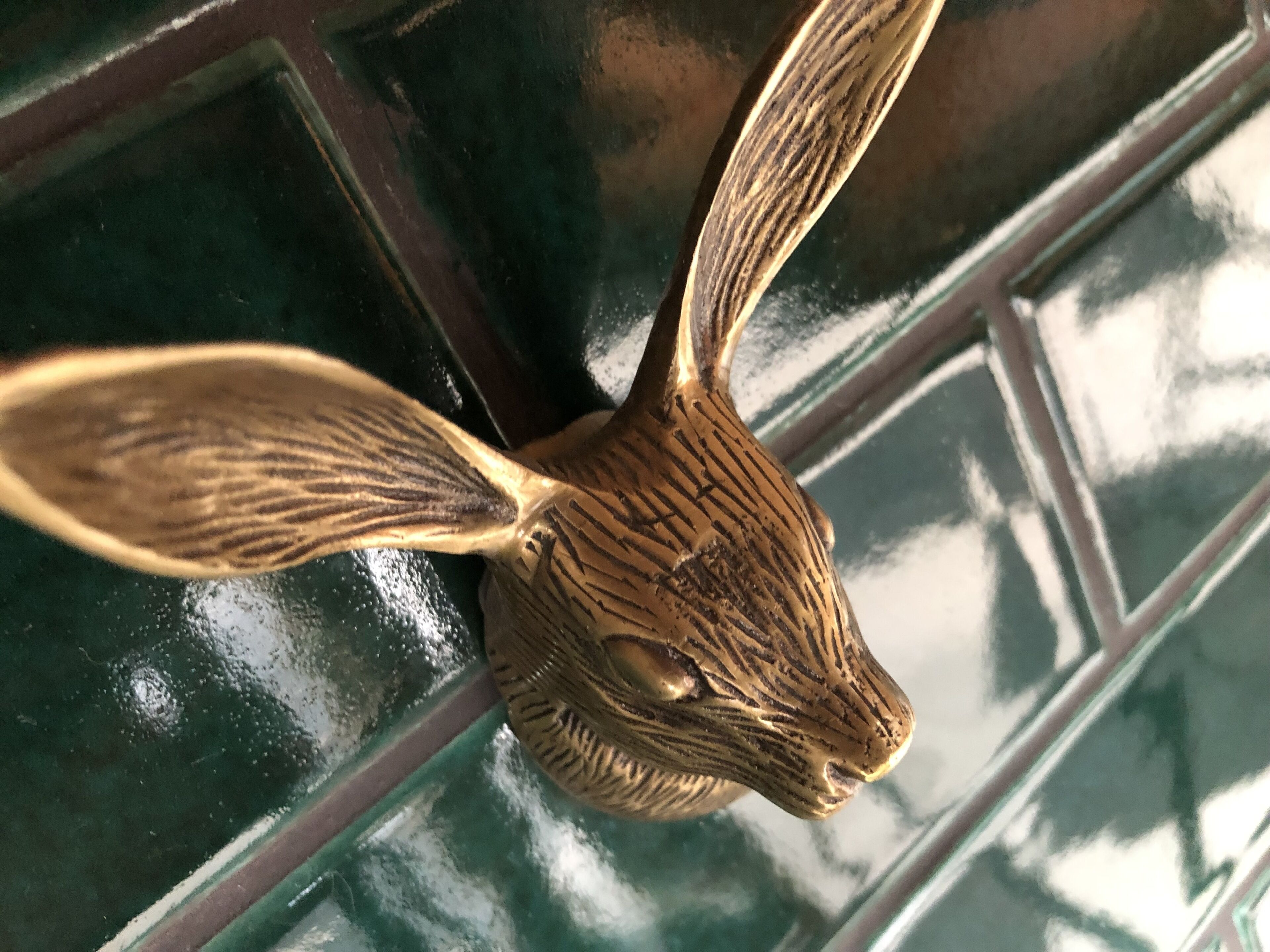 A close-up of a golden rabbit head sculpture with intricate patterns, set against a dark, reflective background.