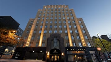 A multi-story hotel with a prominent entrance, a sign reading 'HOTEL DECO', and a clear sky in the background.