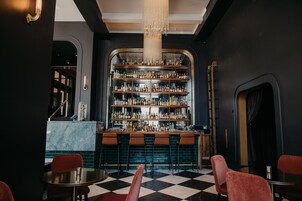 Un espace bar avec un sol à carreaux, des tabourets de bar et une variété de bouteilles exposées sur des étagères.