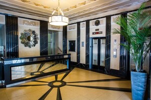 Un hall d’entrée doté d’un sol au motif géométrique, d’un grand miroir et d’un lustre moderne.