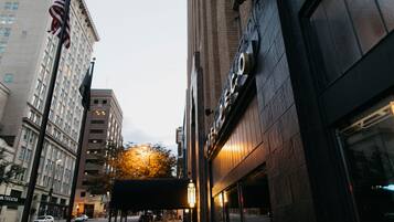 A street view with a building featuring a large American flag and a theater sign.