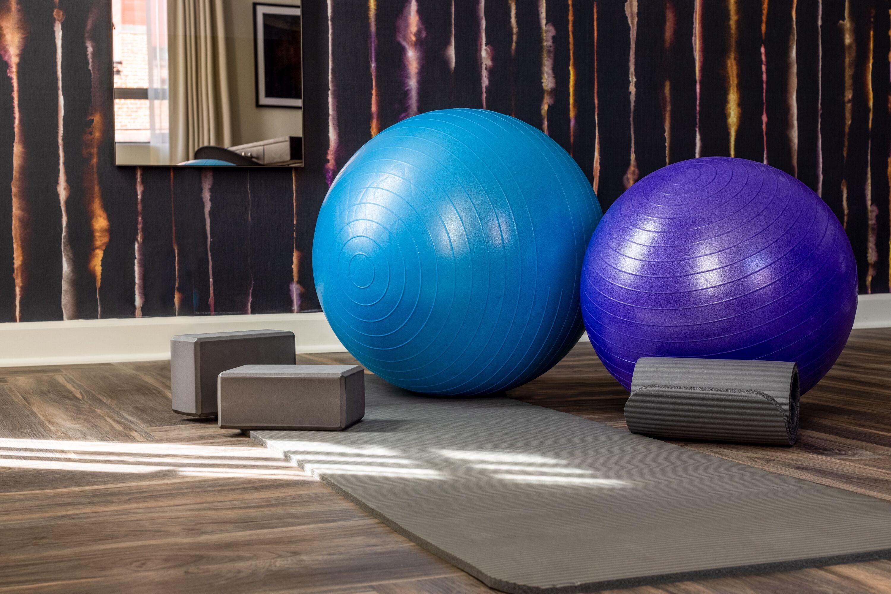A room with two large exercise balls, a yoga mat, and a small gray box.