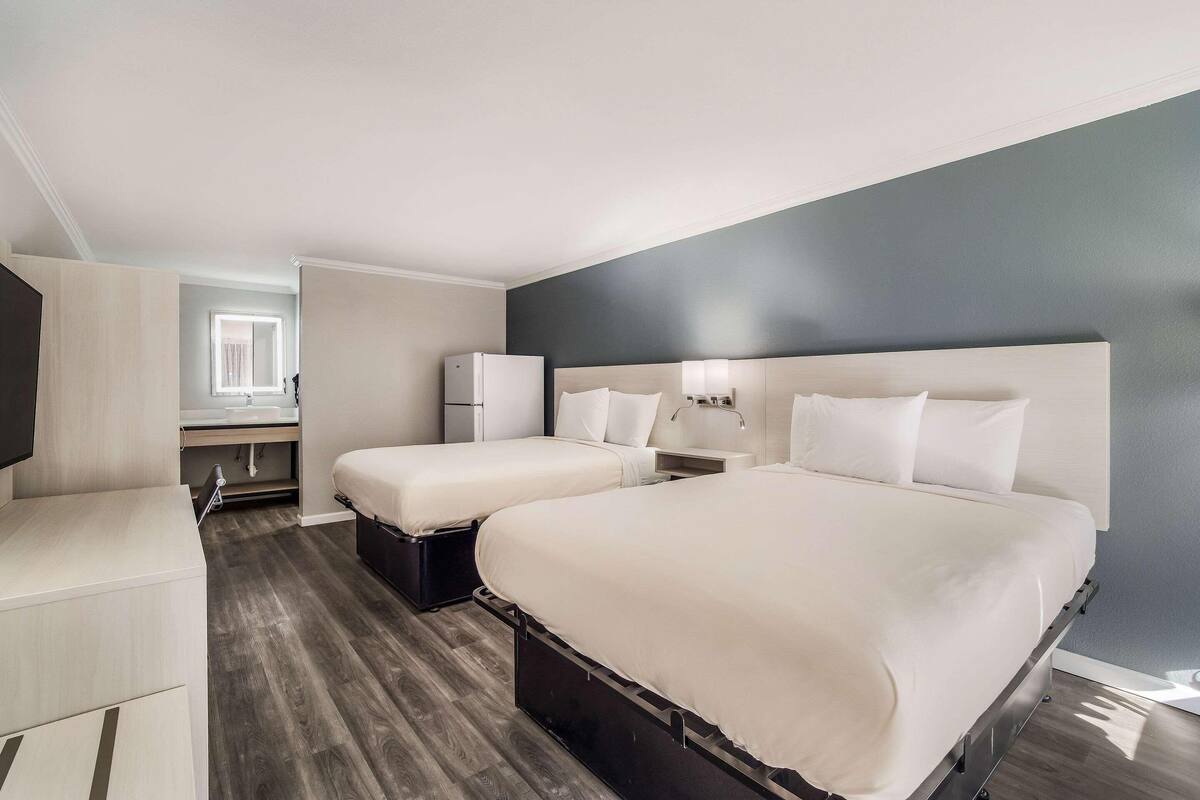 Quarto de hotel moderno com uma cama grande, mesas de cabeceira, escrivaninha e uma janela.