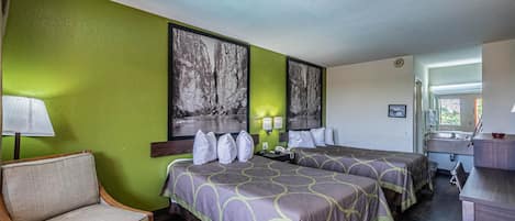 A hotel room with two beds, a chair, a desk, and a window.