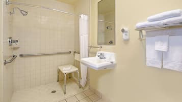 Une salle de bain équipée d’une douche, d’un lavabo, d’un miroir et d’un porte-serviettes.