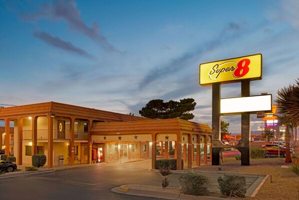 A motel with a large 'Super 8' sign, multiple balconies, and a covered parking area.