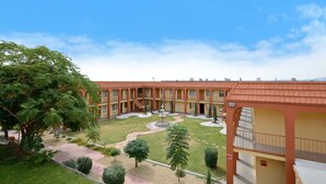 A courtyard with a fountain, surrounded by trees and a building with multiple balconies. - Super 8 by Wyndham El Paso Airport (El Paso)