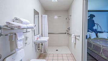 A bathroom with a shower, toilet, and sink, equipped with grab bars and a towel rack.
