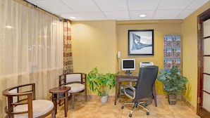 A room with a desk, two chairs, a computer, a monitor, a telephone, and two potted plants. - Super 8 by Wyndham El Paso Airport (El Paso)