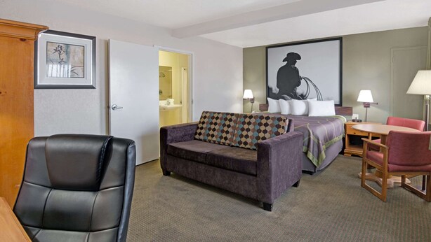 A hotel room with a sofa, a chair, a bed, and a desk. - Super 8 by Wyndham El Paso Airport (El Paso)