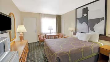 A hotel room with a bed, a desk, a chair, a TV, and a large wall map.