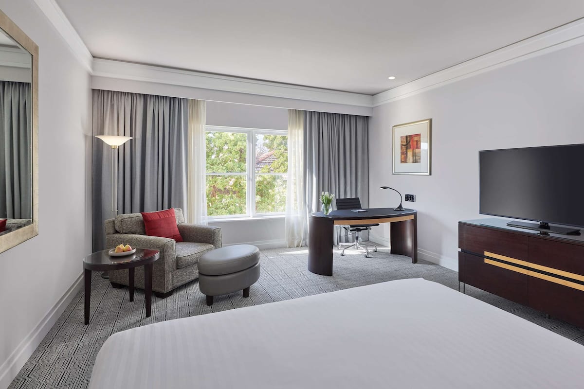 Een hotelkamer met een groot bed, een bureau, een stoel, een bank en een televisie.