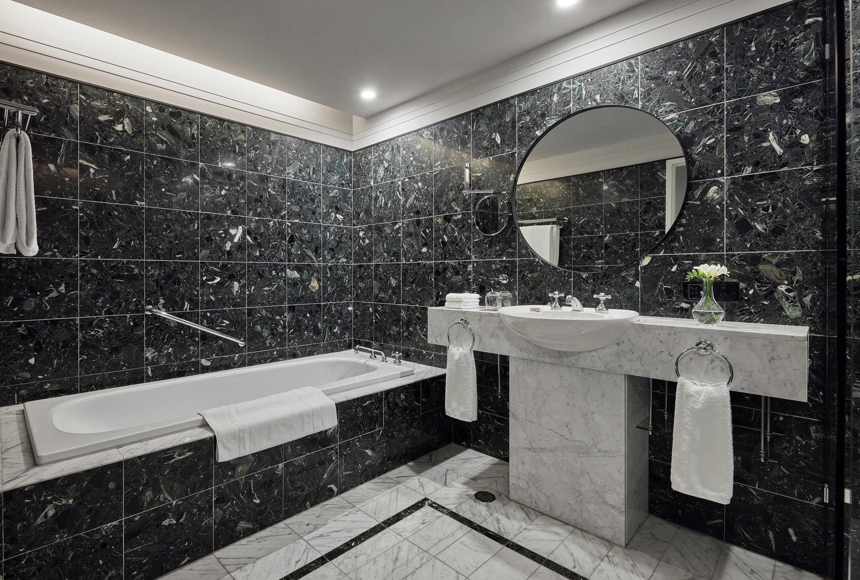 A modern bathroom with a bathtub, two sinks, and a large mirror.
