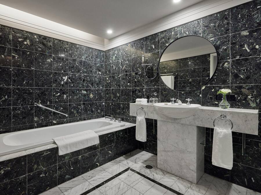 A modern bathroom with a bathtub, two sinks, and a large mirror.