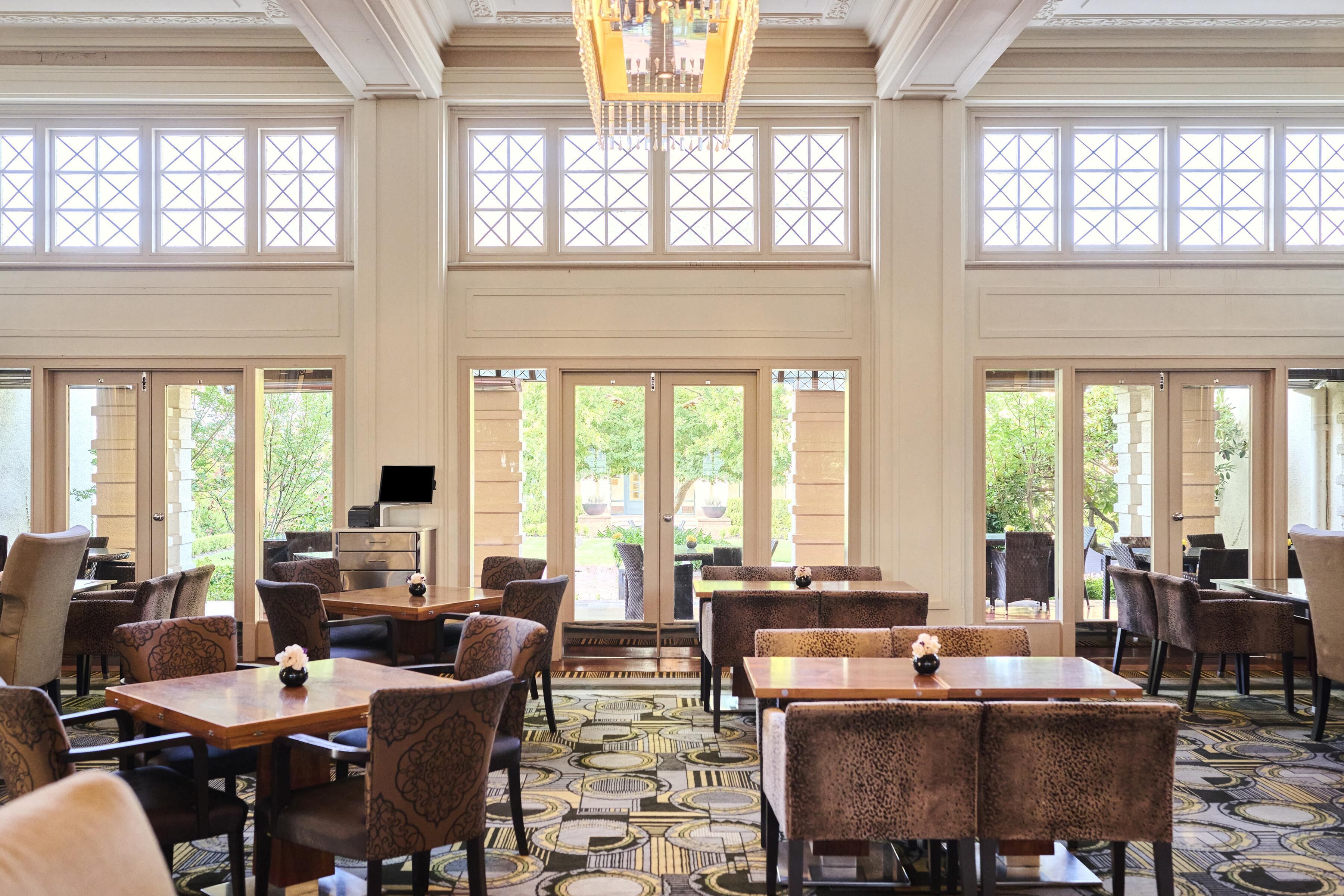 A spacious dining area with high ceilings, large windows, and a patterned carpet.