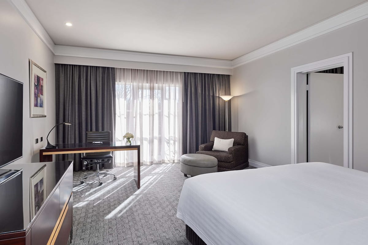 Een hotelkamer met een bed, een bureau, een stoel, een televisie en een deur.