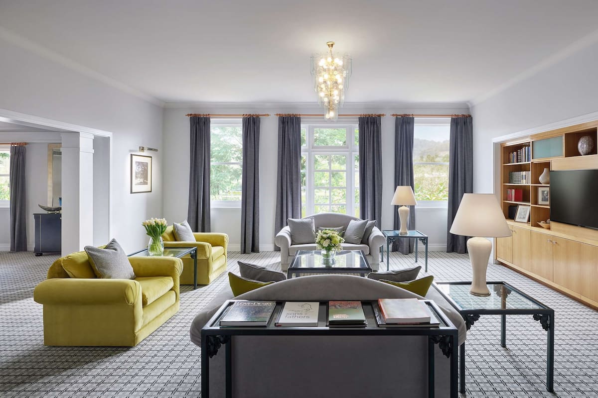 Een moderne woonkamer met een bank, fauteuils, een salontafel en een televisie.