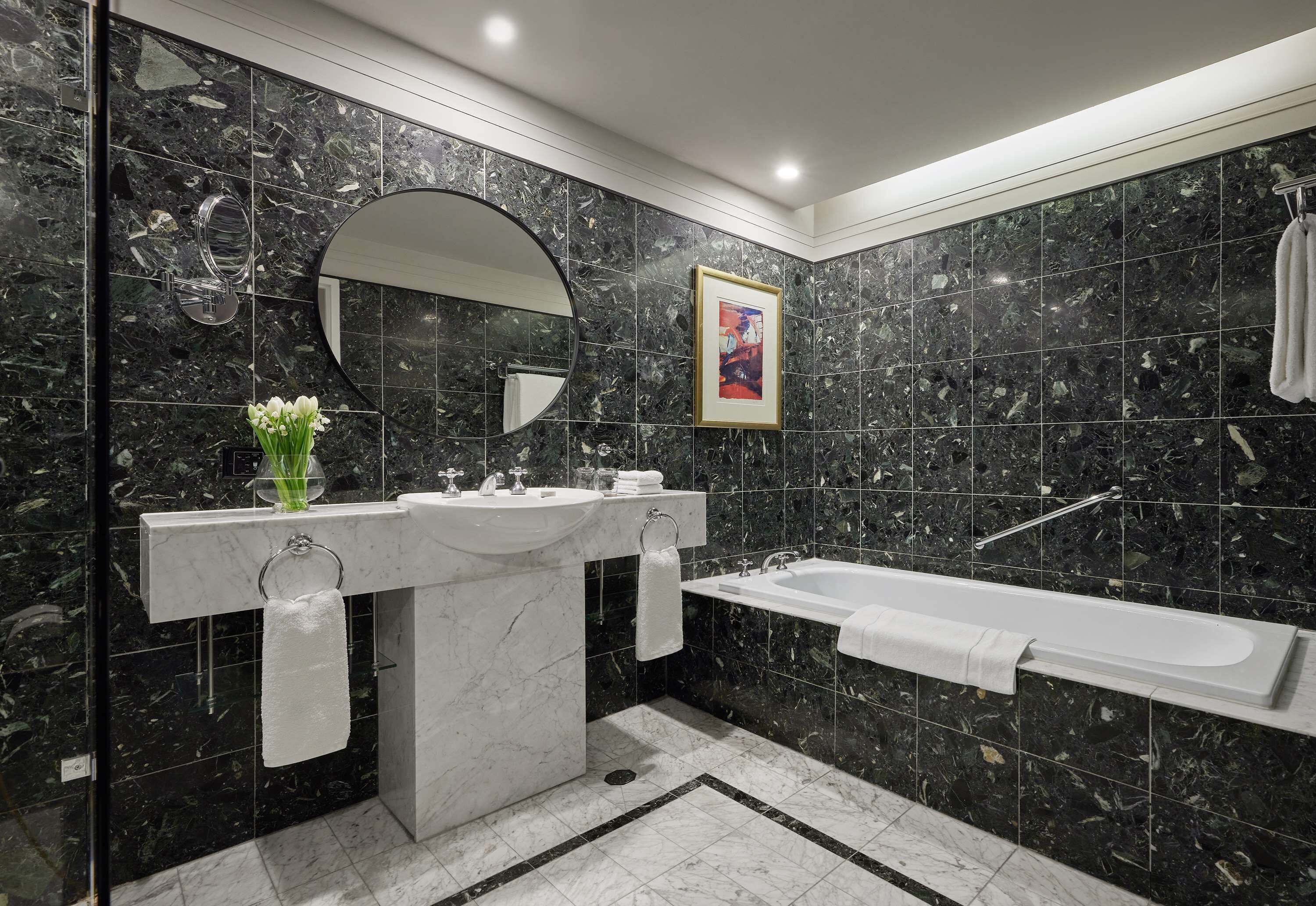 A modern bathroom with a marble sink, a bathtub, and a large mirror.