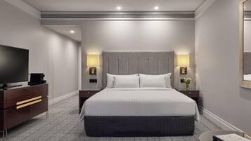 Ein Hotelzimmer mit einem großen Bett, einem Fernseher, einer Kommode und zwei Nachttischlampen.