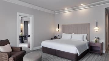 A hotel room with a large bed, a sofa, a nightstand, and a chair.