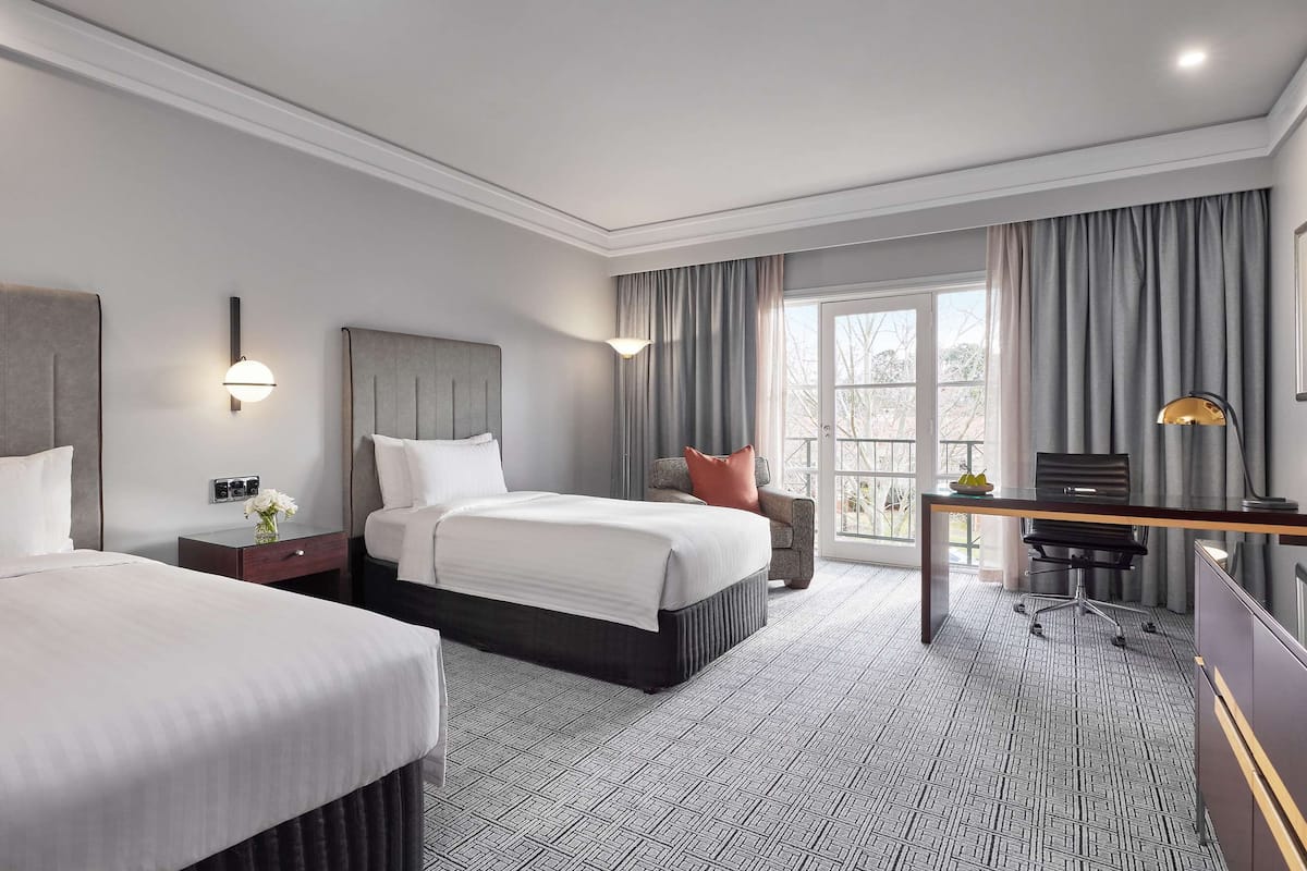 Een moderne hotelkamer met een groot bed, een bureau met stoel, een televisie en een raam met gordijnen.
