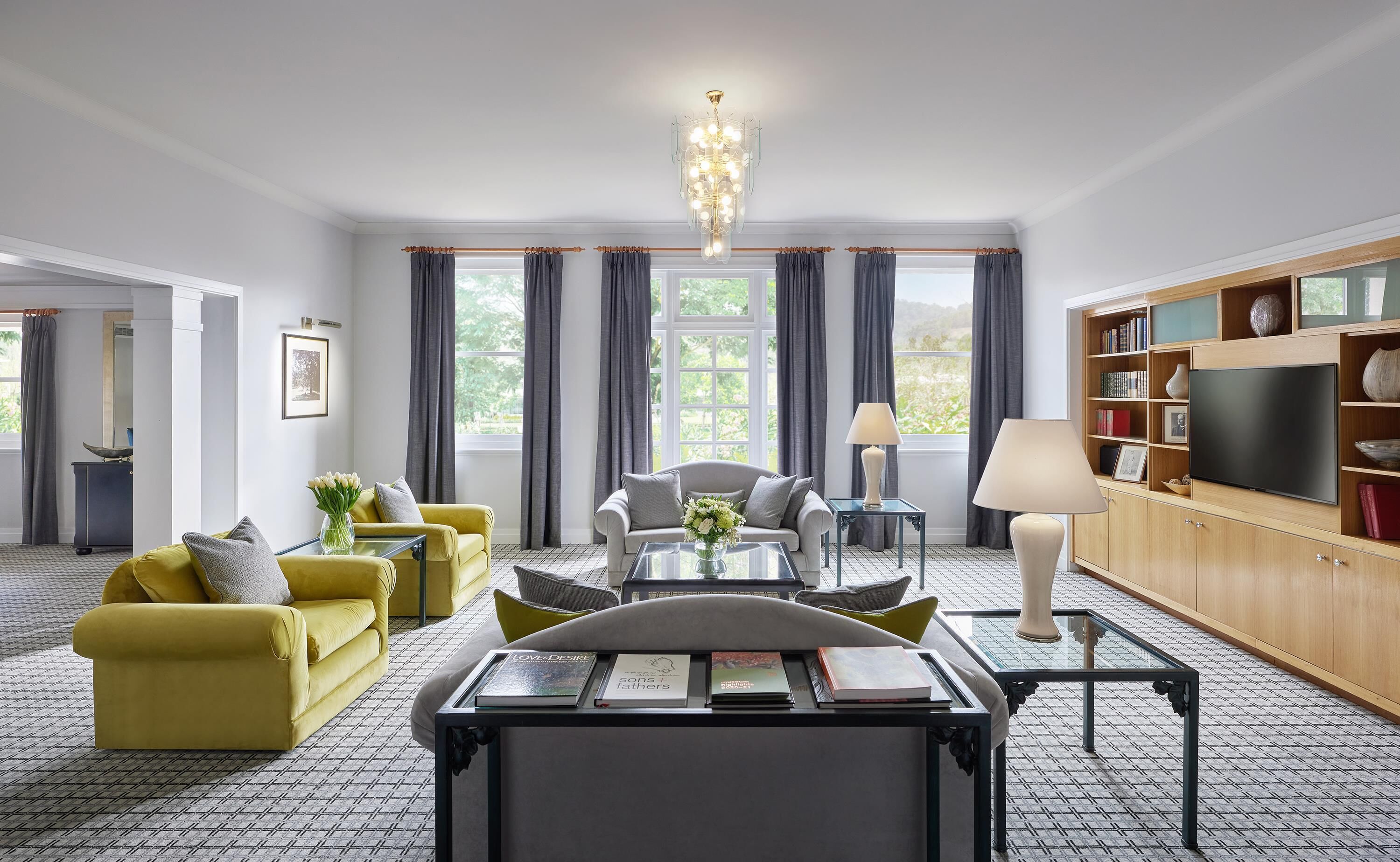 A modern living room with a sofa, armchairs, a coffee table, and a TV.