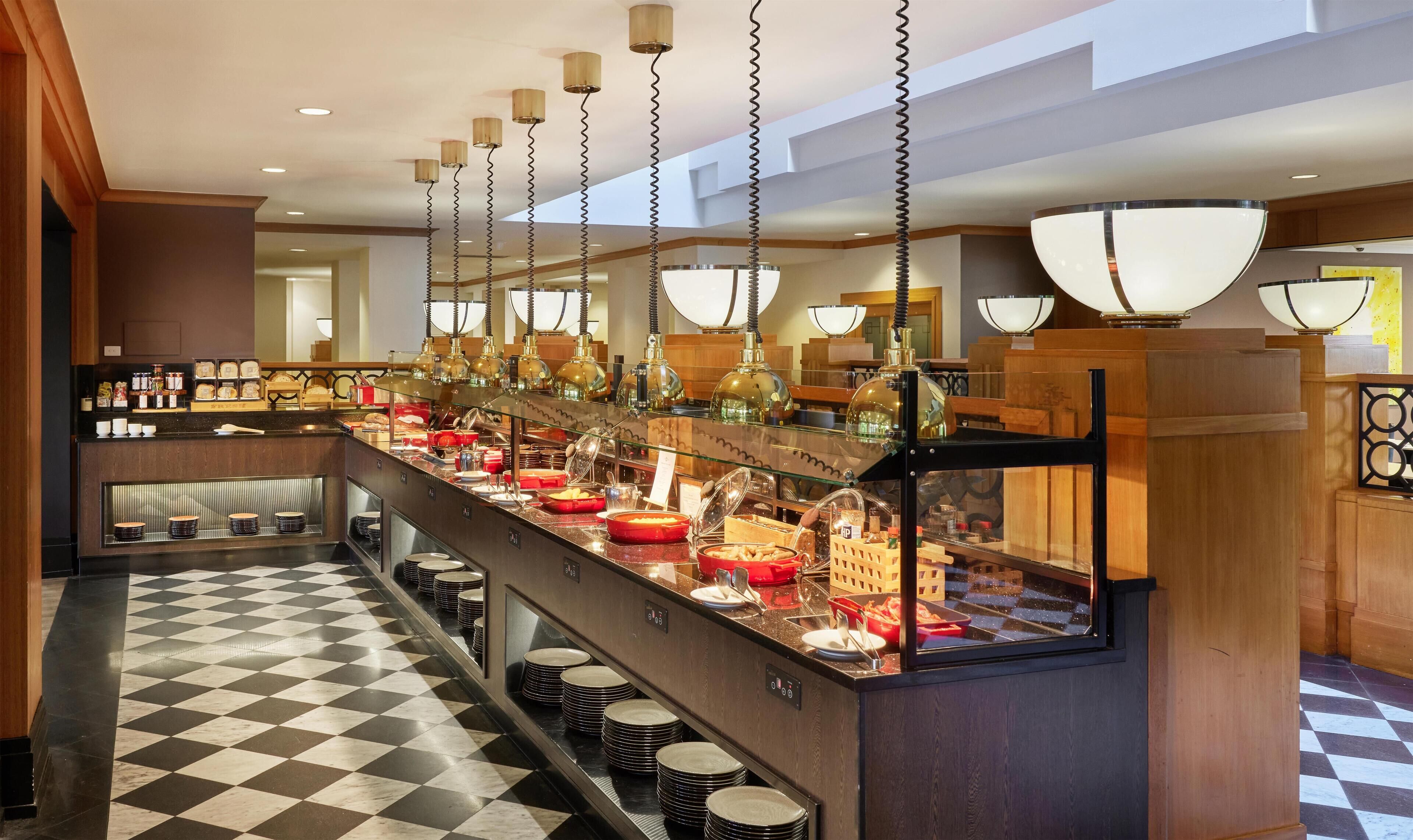 A buffet setup with a checkered floor, multiple serving stations, and hanging pendant lights.