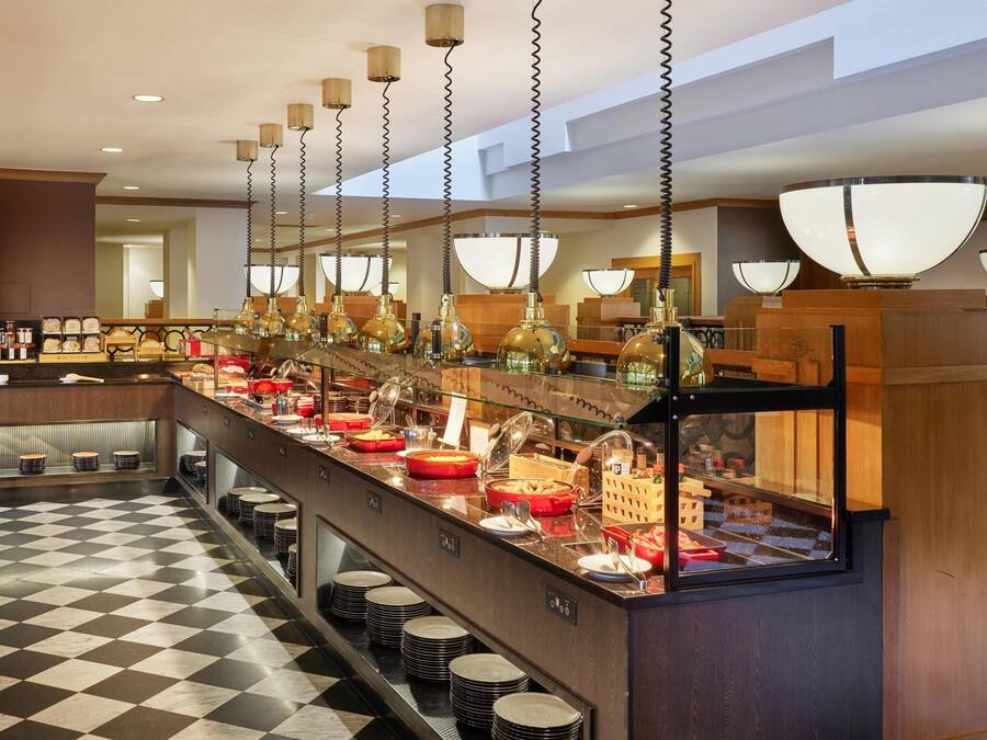 A buffet setup with a checkered floor, multiple serving stations, and hanging pendant lights.