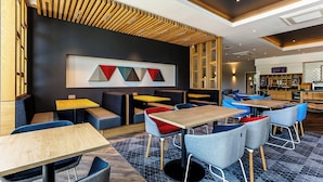 Un intérieur de restaurant moderne, agrémenté d’éléments en bois, avec une palette de couleurs en noir et blanc et une variété de types de sièges, notamment des banquettes et des tables.