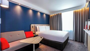 Une chambre d’hôtel avec un lit, un canapé, une petite table et un téléviseur.