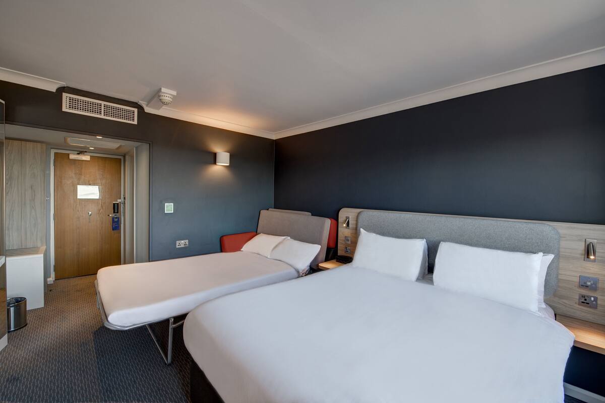 A hotel room with two single beds, a desk, and a chair.