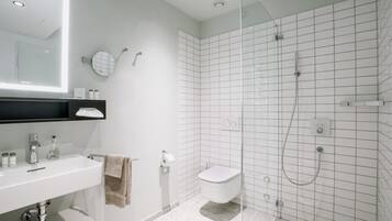 Un baño moderno con ducha de vidrio, lavamanos blanco y retrete.