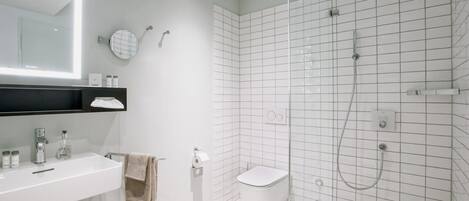 Une salle de bain moderne avec une douche à parois de verre, un lavabo blanc et des toilettes.
