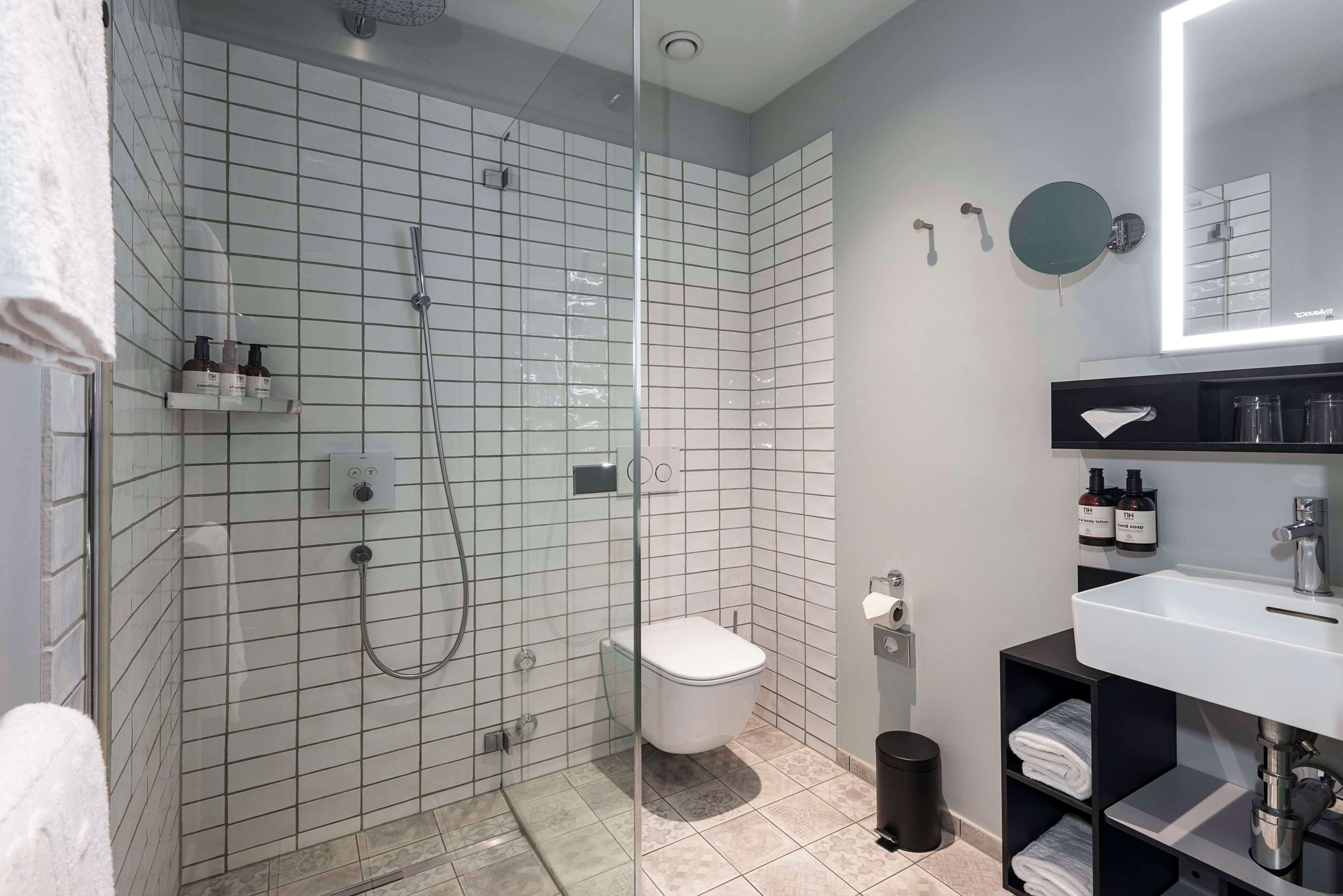 A modern bathroom with a glass-enclosed shower, a white toilet, and a black vanity with a mirror.