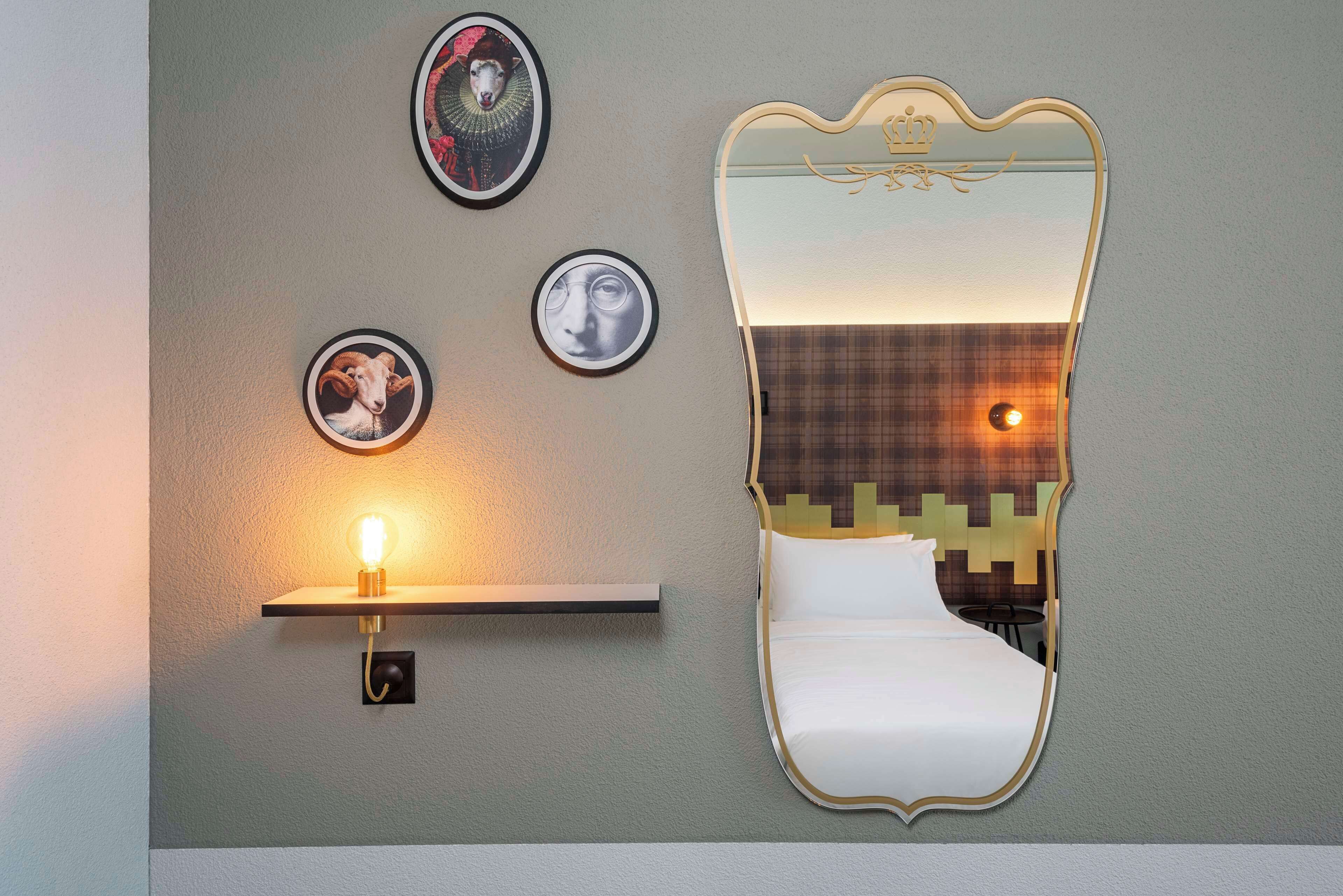 Ein Zimmer mit einem Bett, einem Wandspiegel und drei gerahmten Bildern.