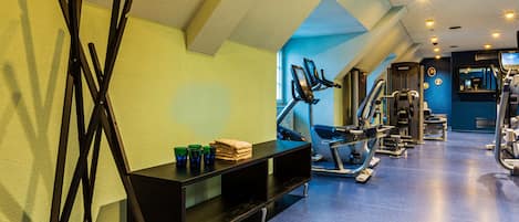 A gym with exercise equipment, a black bench, and a mirror.