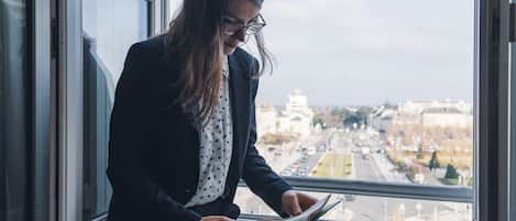 A person sitting by a window with a view of a cityscape.