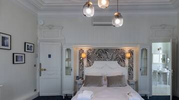 A hotel room with a large bed, a decorative headboard, a nightstand, a bedside table, and a mirror.