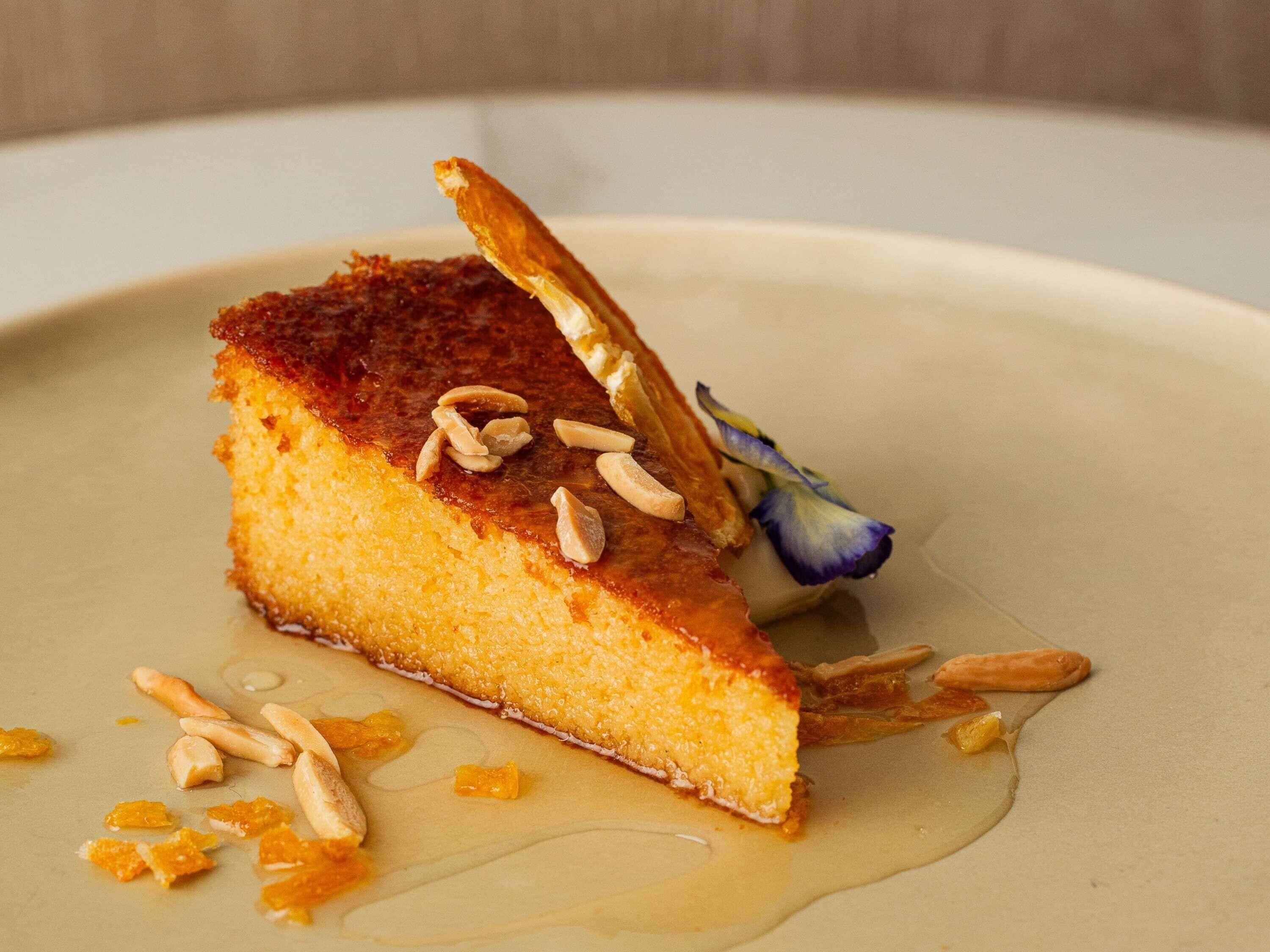 A dessert with almonds and a flower on a plate.