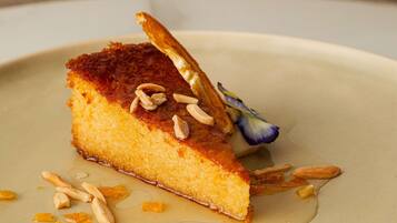 A dessert with almonds and a flower on a plate.