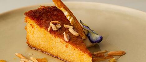 A dessert with almonds and a flower on a plate.