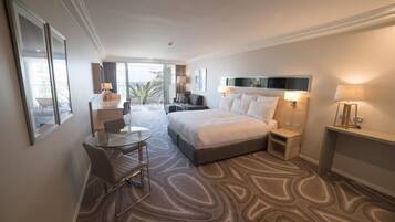 A hotel room with a bed, a desk, and a chair. There is a balcony with a view.