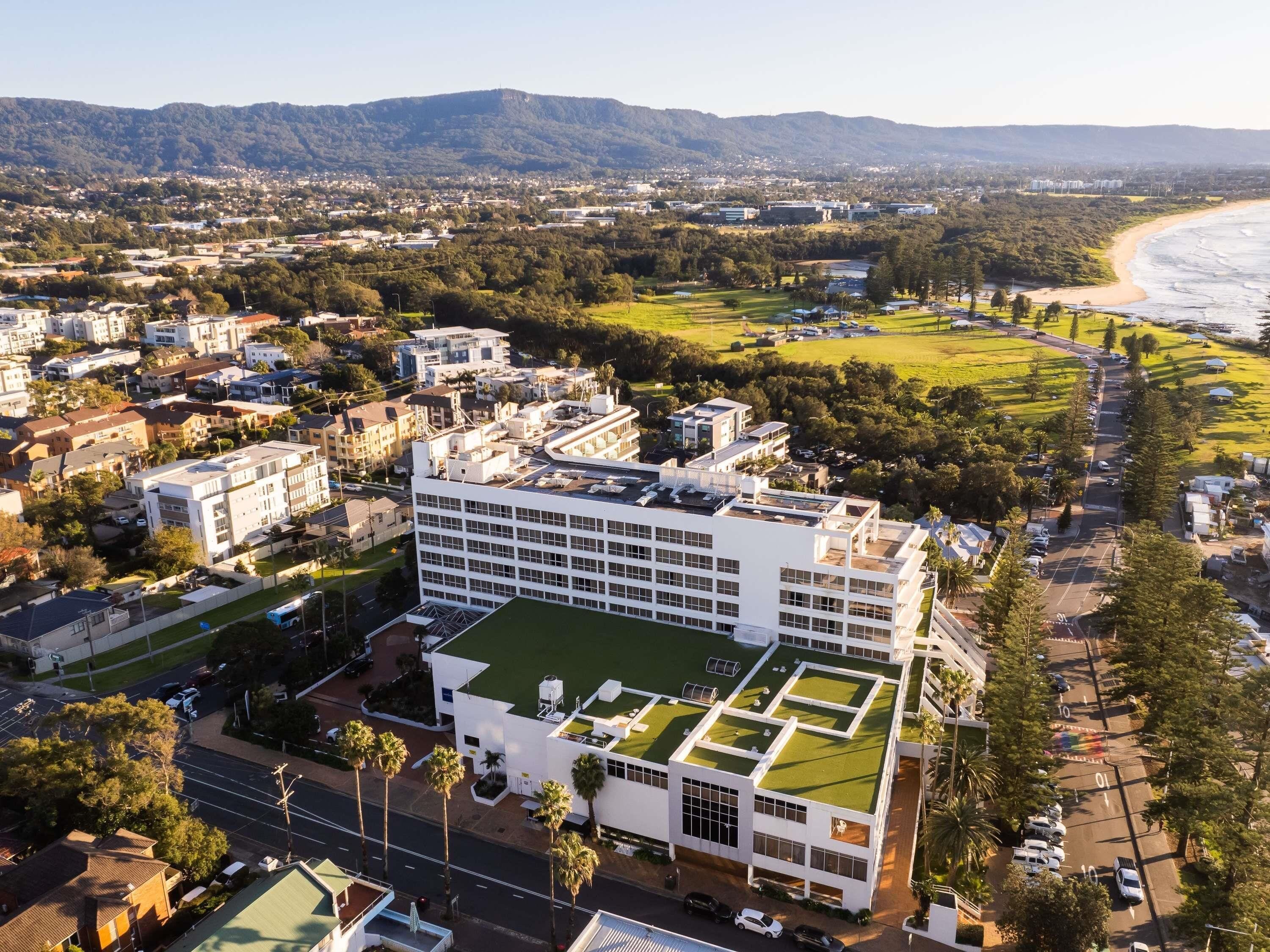 A modern building with a flat roof and a green lawn area.