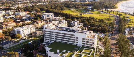 A modern building with a flat roof and a green lawn area.
