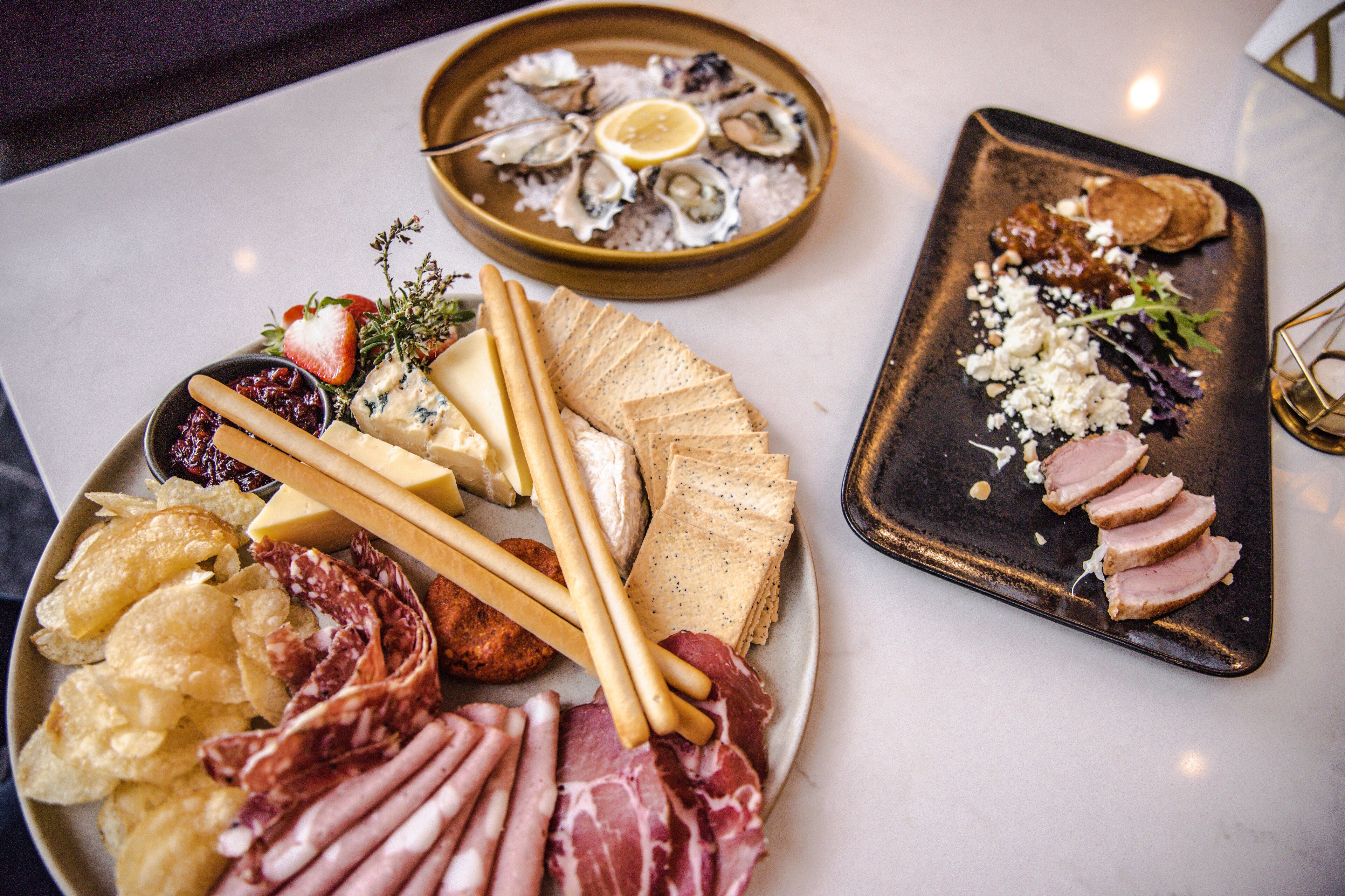 A charcuterie board with various meats, cheeses, crackers, and fruits.