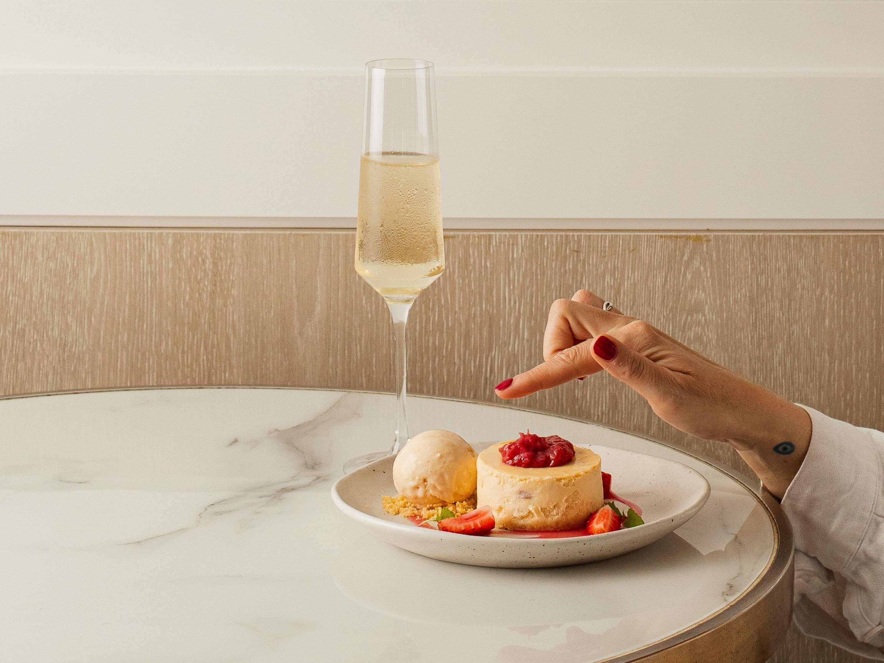 Um prato de sobremesa com um copo de vinho branco sobre uma mesa de mármore.