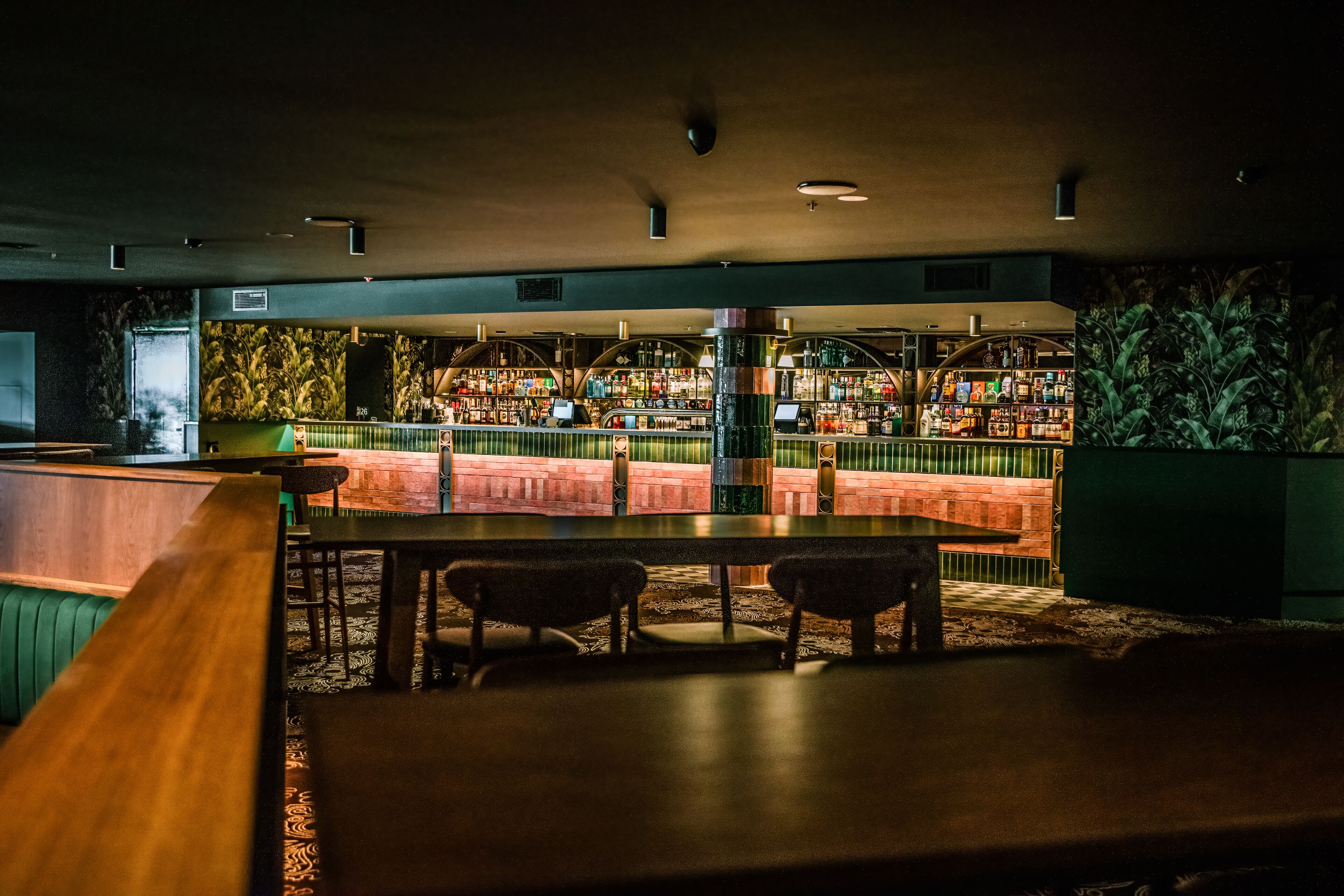 A bar area with a counter, seating, and a view of the bar shelves stocked with bottles.